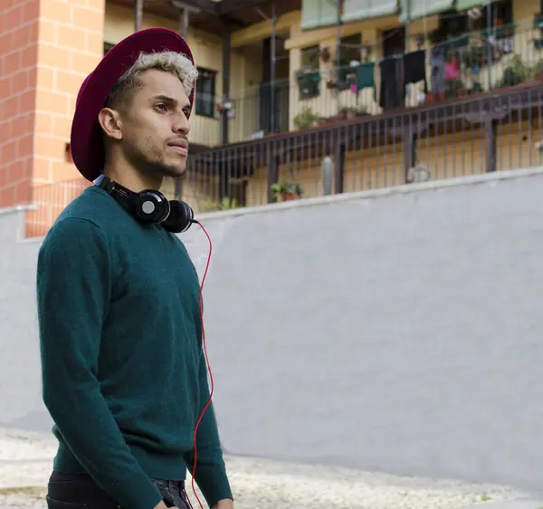 Kulaklıklı ve kırmızı şapkalı genç adam şehirde.