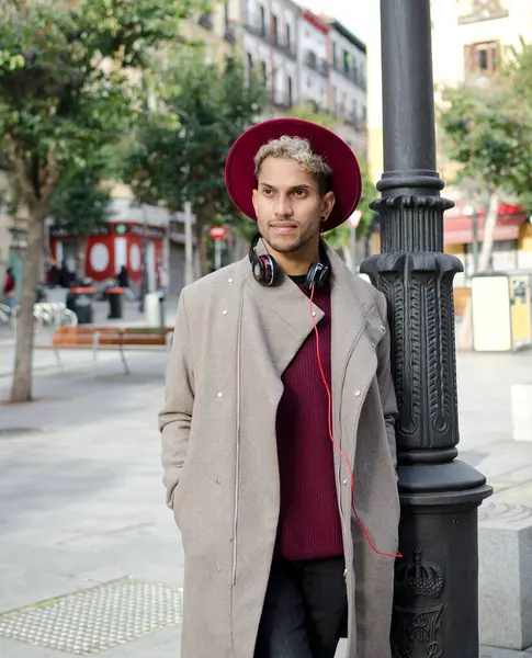 Kulaklıklı ve kırmızı şapkalı genç adam şehirde.