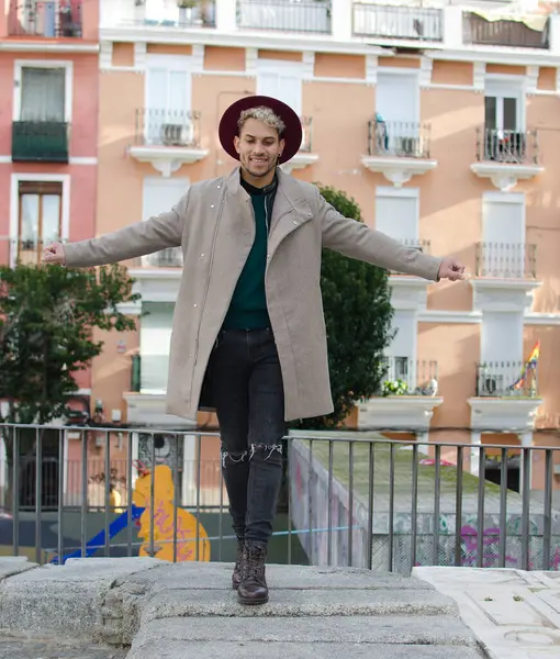 Gri ceketli, kırmızı şapkalı, sokakta dengeyi sağlayan genç bir model.