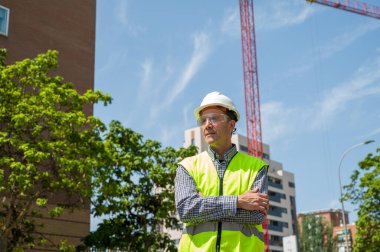 Güvenlik miğferi, yansıtıcı yeleği ve güvenlik gözlüğü olan profesyonel bir inşaat işçisi.