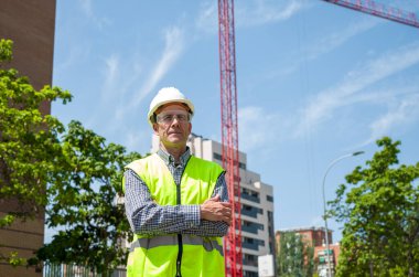 Güvenlik miğferi, yansıtıcı yeleği ve güvenlik gözlüğü olan profesyonel bir inşaat işçisi.