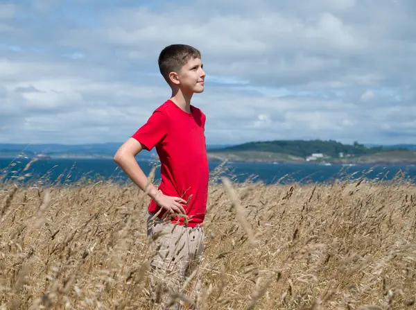 Bir çocuk kıyıda duruyor, rüzgar güçlü esiyor.