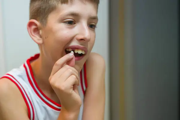 Kafkasyalı çocuk, parmaklarının arasında bir süt dişi tutuyor.