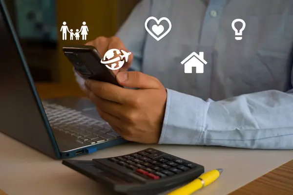 Ofiste akıllı telefon ve laptop kullanan bir iş adamı. Adam sosyal medyayı tarıyor, e-postaları kontrol ediyor, iş işlemlerini yönetiyor, uzaktan çalışıyor. Modern teknoloji işi kolaylaştırır. Etkin zaman yönetimi.
