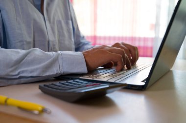 Bilgisayarın klavyesinde yazı yazan adam eli, ofiste dizüstü bilgisayar kullanan iş adamı veya öğrenci, çevrimiçi öğrenme, internet pazarlaması, evden çalışma, ofis iş yeri serbest kavramı