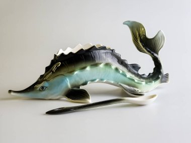 Beyaz arka planda mersin balığı şeklinde kaşığı olan havyar kasesi. Özgün yemekler..