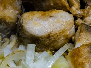 Kızarmış Habbsi hake ya da kızartma sırasında tavada soğanlı Arjantin hake..