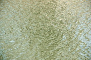 Gün batımı ışınlarında su yüzeyi, nehir dalgaları ya da yakın çekim dalgalı okyanus. Doğal arka plan. Soyut arkaplan, doku.