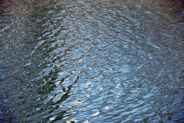 Bulutlu havada su yüzeyi, küçük dalgalı nehir veya okyanus dalgaları, sakin ve yakın çekim. Doğal arka plan. Soyut arkaplan, doku.