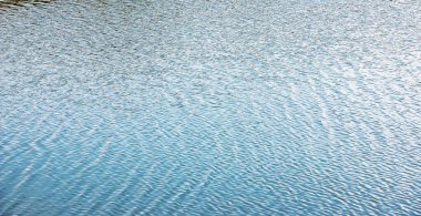 Gün batımında su yüzeyi, küçük dalgalı nehir dalgaları, sakin ve yakın çekim. Doğal arka plan. Soyut arkaplan.