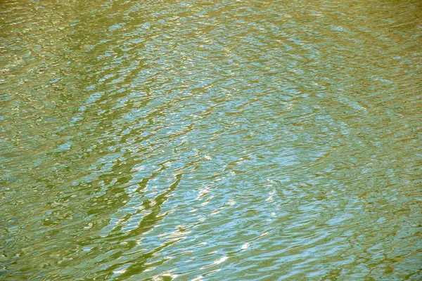 Gün batımı ışınlarında su yüzeyi, nehir dalgaları ya da küçük dalgalı okyanus, sakin ve yakın çekim. Doğal arka plan. Soyut arkaplan.