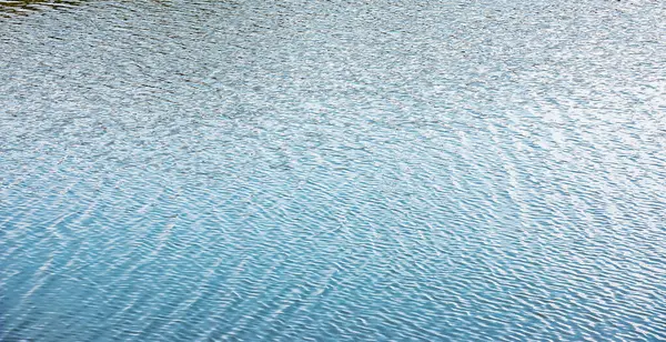 Gün batımında su yüzeyi, küçük dalgalı nehir dalgaları, sakin ve yakın çekim. Doğal arka plan. Soyut arkaplan.