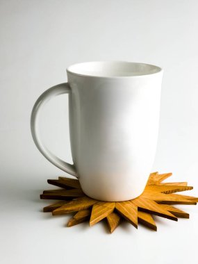 Beyaz kupa, beyaz arka planda izole edilmiş kar tanesi şeklinde ahşap sıcak stantta duruyor..