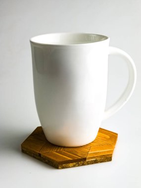 Altıgen şeklinde ahşap sıcak ayakta beyaz fincan beyaz arka planda izole.