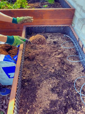 Eldivenli adamların elleri baharda ekmek için toprağı hazırlar. Bir malayla toprağı dağıtıyorlar..