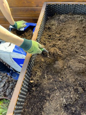 Yeşil eldivenli adamların elleri toprağı ilkbaharda ekime hazırlıyor. Toprak bir kürekle dağılmış..