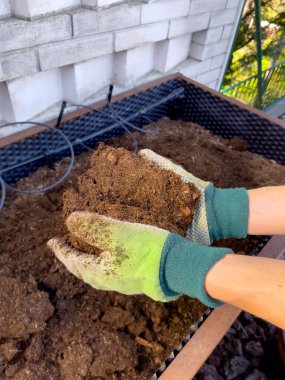 Toprak çiftçinin güçlü ellerinde, arka plandaki adamlar, üst tabaka. Tarım, bahçıvanlık veya ekoloji konsepti modellemesi.