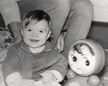 Elinde oyuncak bir bebekle bir yaşındaki bir kızın klasik portresi. Taklacı bebek. 1995 'ten kalma eski bir fotoğraf.