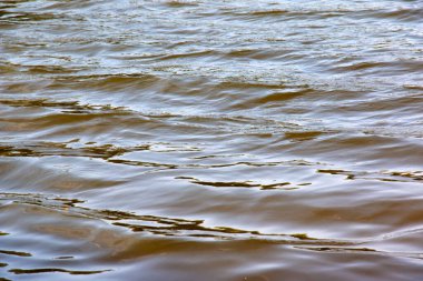 Dinyeper Nehri 'nin dalgalı su yüzeyinin arka planı. Sonbaharda batan güneşin ışınlarında nehir suyu. Nehir suyunun doğal rengi.