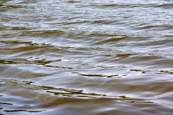 Dinyeper Nehri 'nin dalgalı su yüzeyinin arka planı. Sonbaharda batan güneşin ışınlarında nehir suyu. Nehir suyunun doğal rengi.