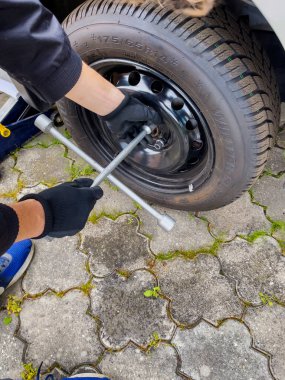 Nitra, Slovakya - 08.05.2025: araba servisi. Tekerlek değiştirme. Mevsimlik lastik değişimi. Tamirci tekerleği iki eliyle ve anahtarla çıkarır..