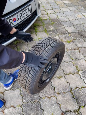 Nitra, Slovakya - 08.05.2025: Bir tamircinin elindeki bir araba tekerleği, değiştirilmesi için kaldırıldı.