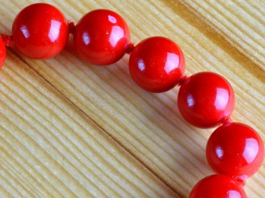 Ahşap arka planda parlak kırmızı mercan boncukları. Yakın plan..