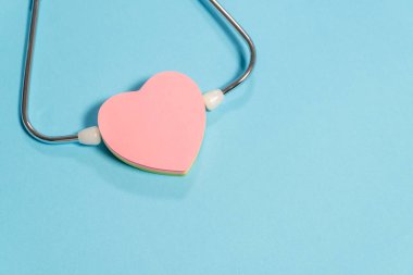 Açık mavi arka planda kalbi olan tek başlı steteskop