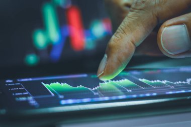 İşadamı geceleyin borsa grafiğiyle akıllı telefondan ekrana dokunuyor.. 