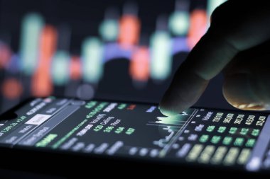 İşadamı geceleyin borsa grafiğiyle akıllı telefondan ekrana dokunuyor.. 