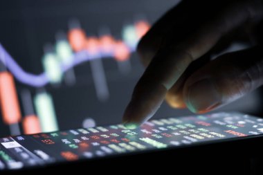 İşadamı geceleyin borsa grafiğiyle akıllı telefondan ekrana dokunuyor.. 