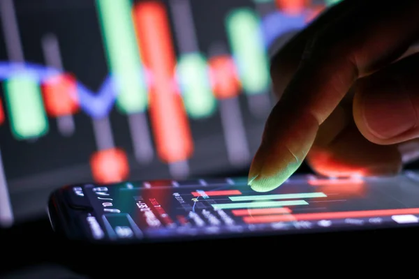 stock image Businessman finger touching screen on smartphone with stock market graph at night. 