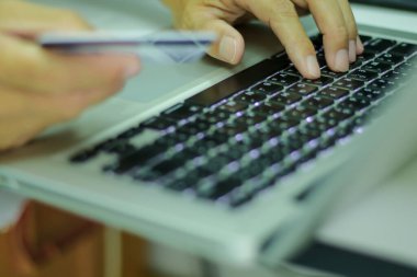 Adamın biri kredi kartıyla online alışveriş yaparak lobi klavyesiyle çalışıyor. İnternetten alışveriş kavramı.