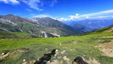 Dağların sakin manzarası engebeli bir heybetle yükseliyor, tepeleri geniş, açık gökyüzüne değiniyor, Kashmir, Pakistan.