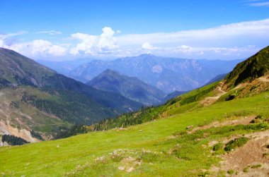 Dağların sakin manzarası engebeli bir heybetle yükseliyor, tepeleri geniş, açık gökyüzüne değiniyor, Kashmir, Pakistan.