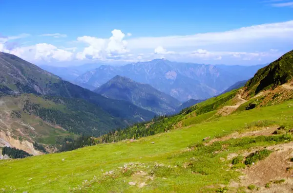 Dağların sakin manzarası engebeli bir heybetle yükseliyor, tepeleri geniş, açık gökyüzüne değiniyor, Kashmir, Pakistan.