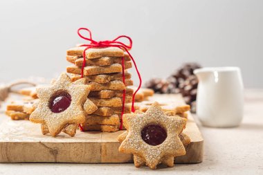 Kurabiye hediyesi. Kırmızı kurdeleyle bağlanmış ahududu reçelli ev yapımı yıldız ya da çiçek şeklinde linzer kurabiyeler. Noel ya da Anneler Günü konsepti. Seçici odak.