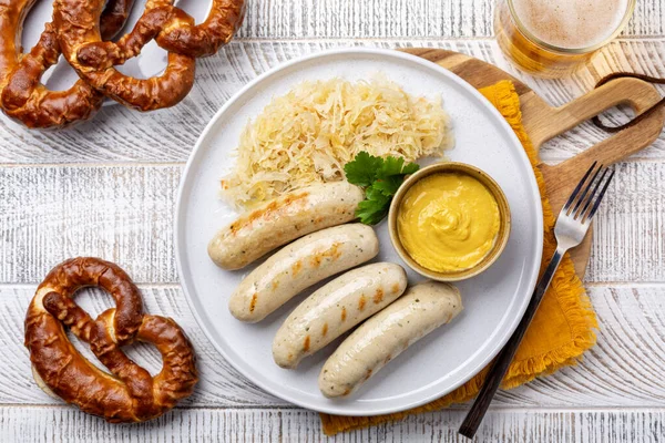 German food. Top view. Bavarian white sausage Weisswurst made from minced veal and pork back bacon, crauti or sauerkraut, mustard and a soft pretzel.