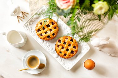 Romantic breakfast. Mini tartlet or pies crust with berries. Espresso coffee cup, hard boiled egg, water, flowers. Directly above.