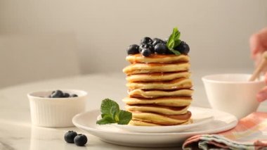 Pancake Stack with blueberries and pouring honey or maple syrup.