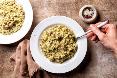 İtalyan pilavlı pilav pilavı sosis ve şalgam yeşili yemek, risotto ve Salsiccia peyniri yemek. Çatal tutan insanlar..
