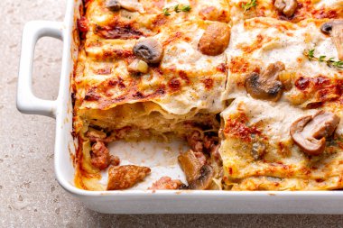 Close-up of homemade casserole with white lasagna with porcini and champignon mushrooms, onion and sausages. Pasta with parmesan cheese and bechamel sauce. clipart
