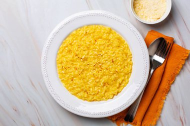 Safran, pirinç, tereyağı, sert peynir ve sebze suyundan yapılmış İtalyan yemeği. Risotto alla milano ya da risotto allo zafferano. Beyaz masa. Üst görünüm.