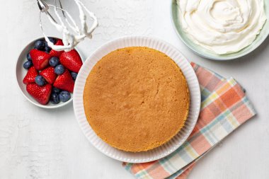 Meyveli, çilekli, yaban mersinli ve kremalı vanilyalı kek pişirip pişiriyorum. Ev yapımı aşçılık, yaz meyveli tatlı. İçeriğin üst görünümü, beyaz arkaplan.