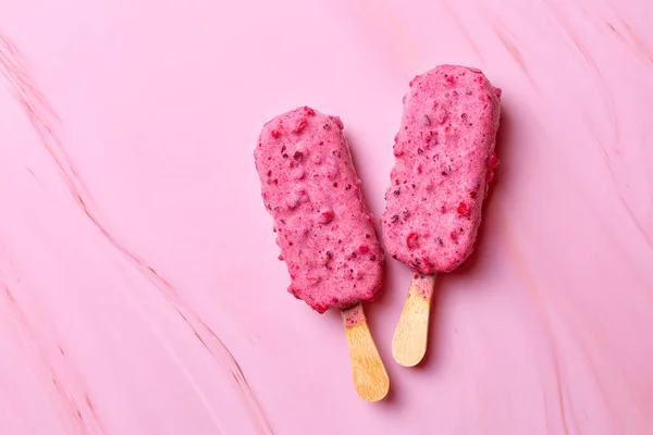 Fruit and berry ice cream on a stick, fresh blueberries and strawberries. Popsicle. Pink, magenta food background. Copy space.