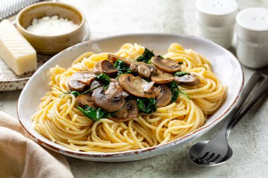 Mantar ve ıspanaklı spagettiye yakın çekim. Parmesan peyniri. Ev yapımı İtalyan makarnası. Hafif arkaplan.