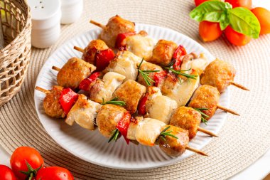 Tavuk, İtalyan sosisi, pastırma ve sebze, dolmalık kebap veya şiş. Akdeniz kebabı, bej bir masada biberiyeli beyaz tabakta yaz yemeği..