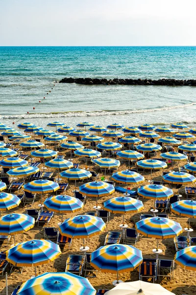 stock image Summer blue yellow beach umbrellas on a sand in the morning, Adriatic sea coast, Abruzzo, Italy. Background. Travel and vacation concept. Vertical image. No people.