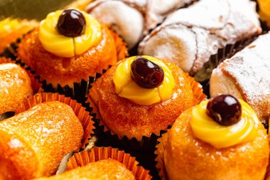 Çeşitli İtalyan hamur işlerinin yakın çekimi. Kirazlı ve kremalı Zeppole di San Giuseppe, cannoli ve baba romu. Seçici odak