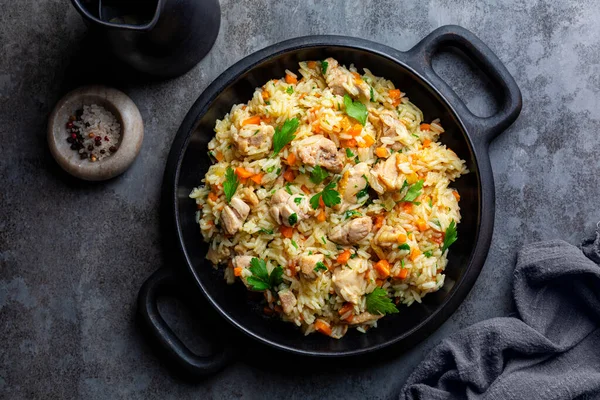 stock image Chicken Pilaf, pilau or biryani. Dish made of long-grain rice, onion, carrots, spices and parsley. Eastern cuisine. Dark background, top view.